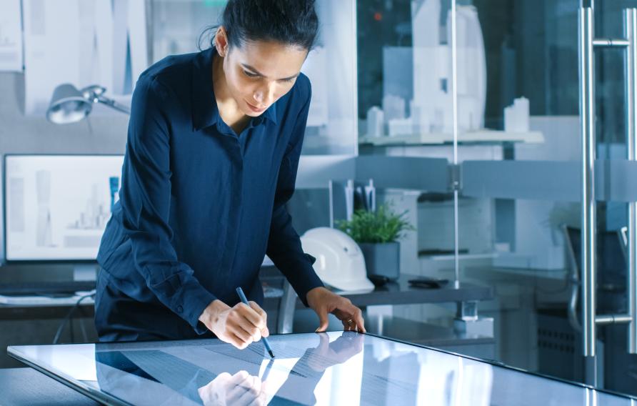 Latina woman in a navy blouse sketches on a whiteboard